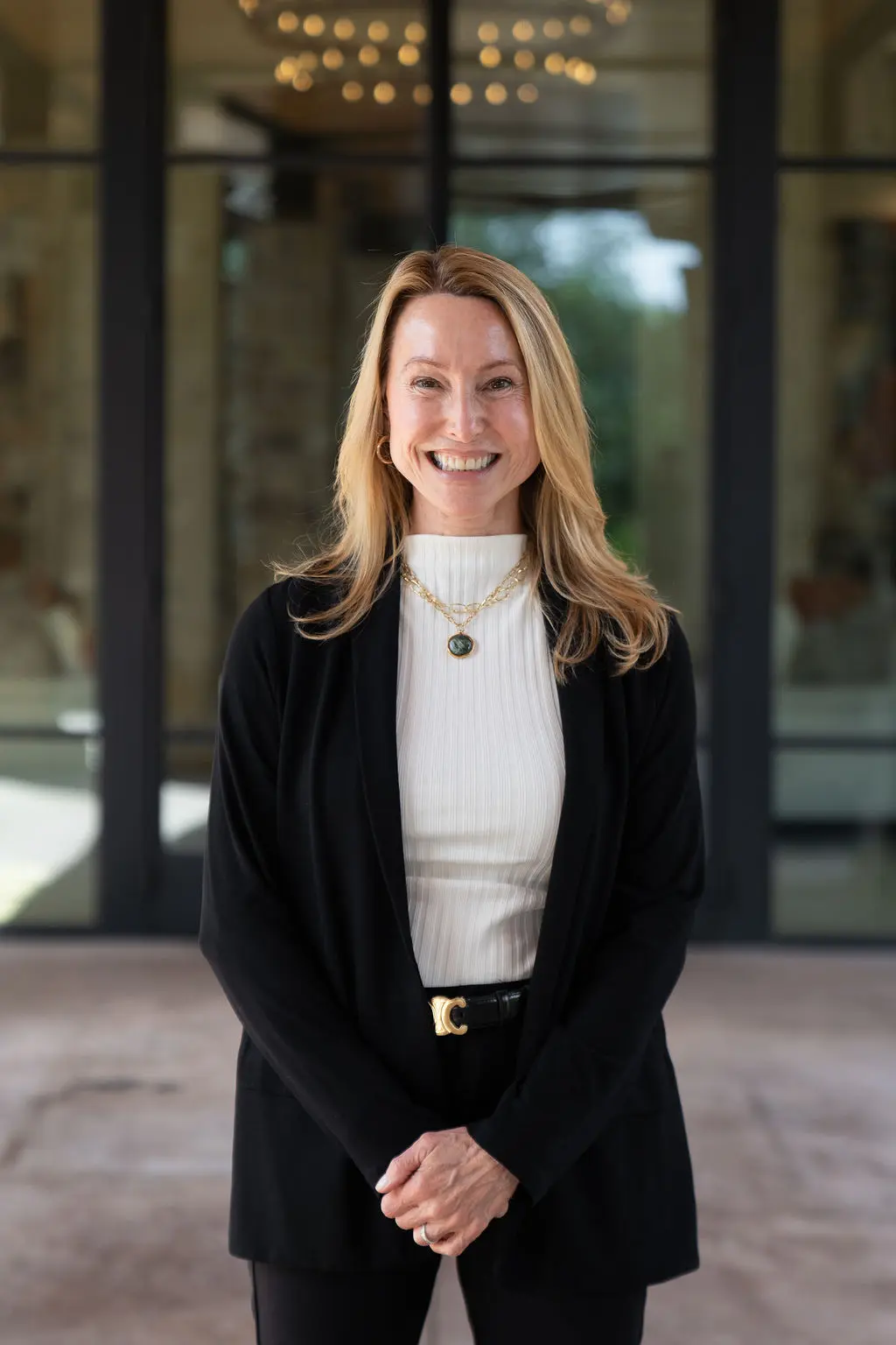 Smiling woman in business casual attire standing outdoors.